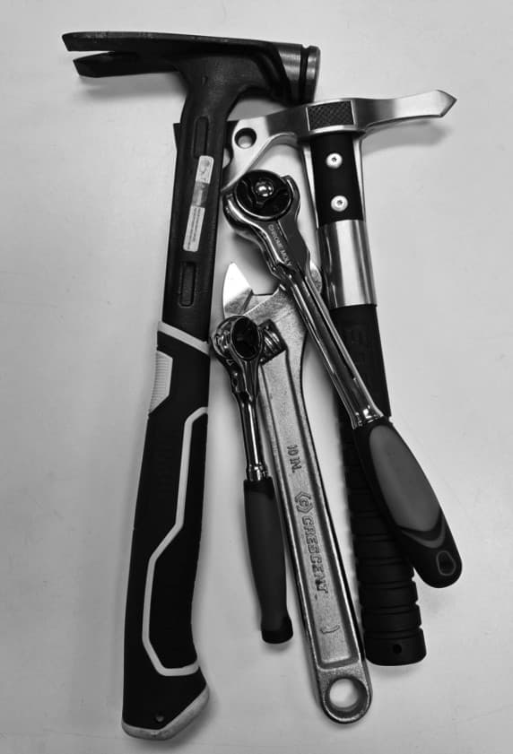 A conventional tool set: framing hammer, hatchet, adjustable wrench and two ratchets laid side by side